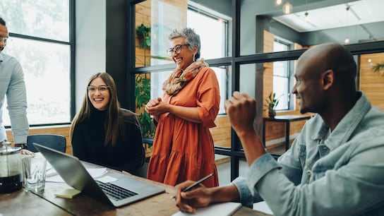 Diverse businesspeople smiling cheerfully during a meeting in a modern office