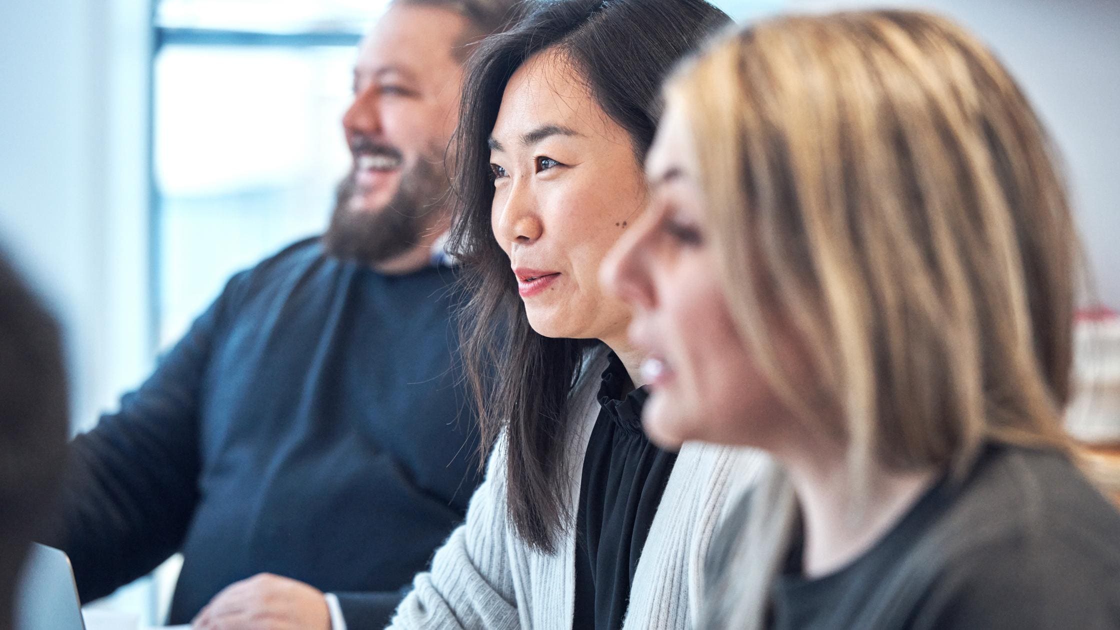 Three people interacting in a meeting at a table