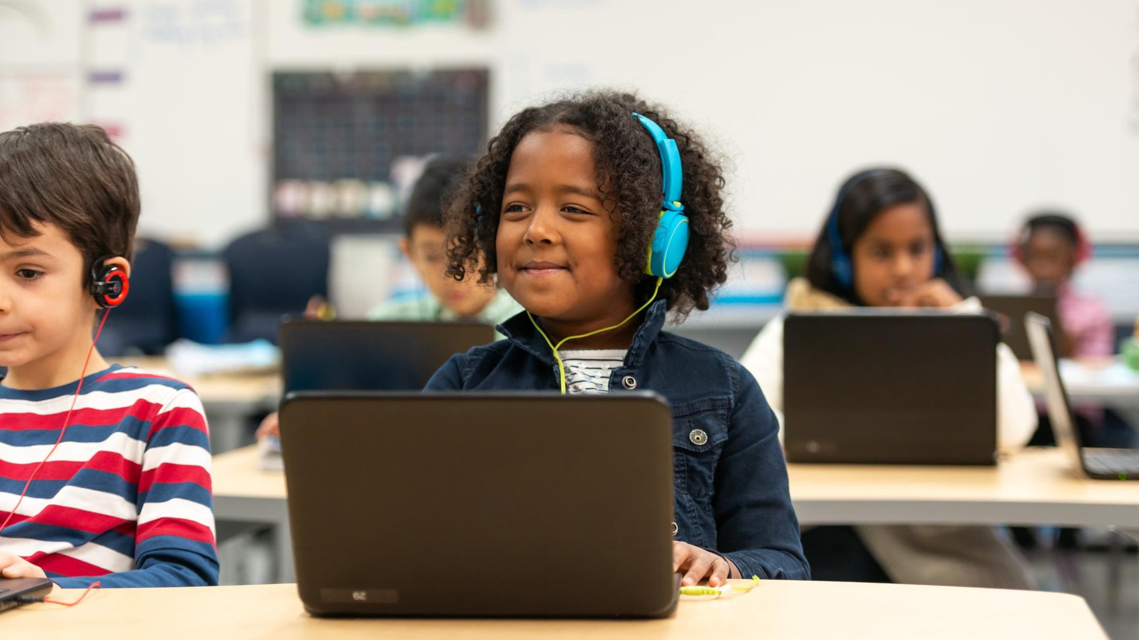ICT - A cute little girl of African descent sits at a computer while learning about some interesting facts 
