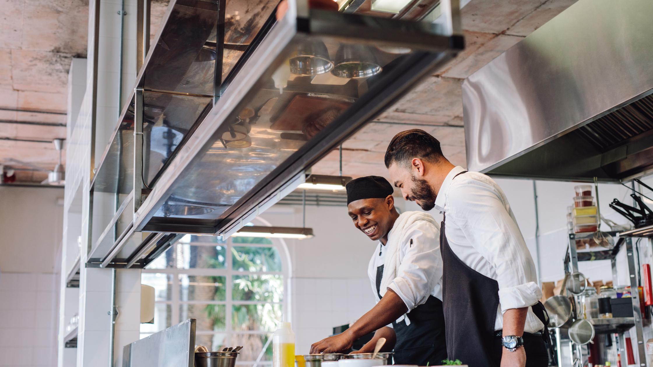 Food safety - male chefs cooking food at cafe kitchen