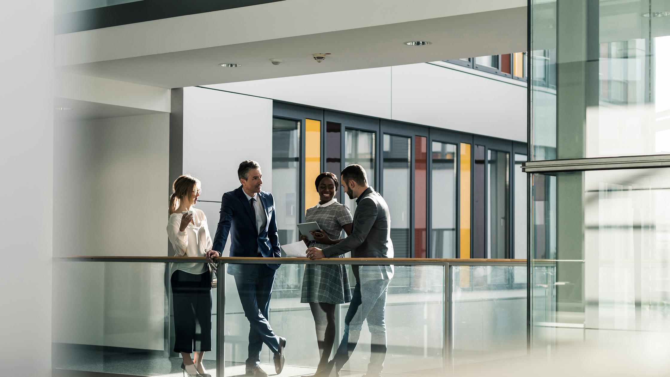 Business people talking on office floor - Corporate colleagues in a meeting