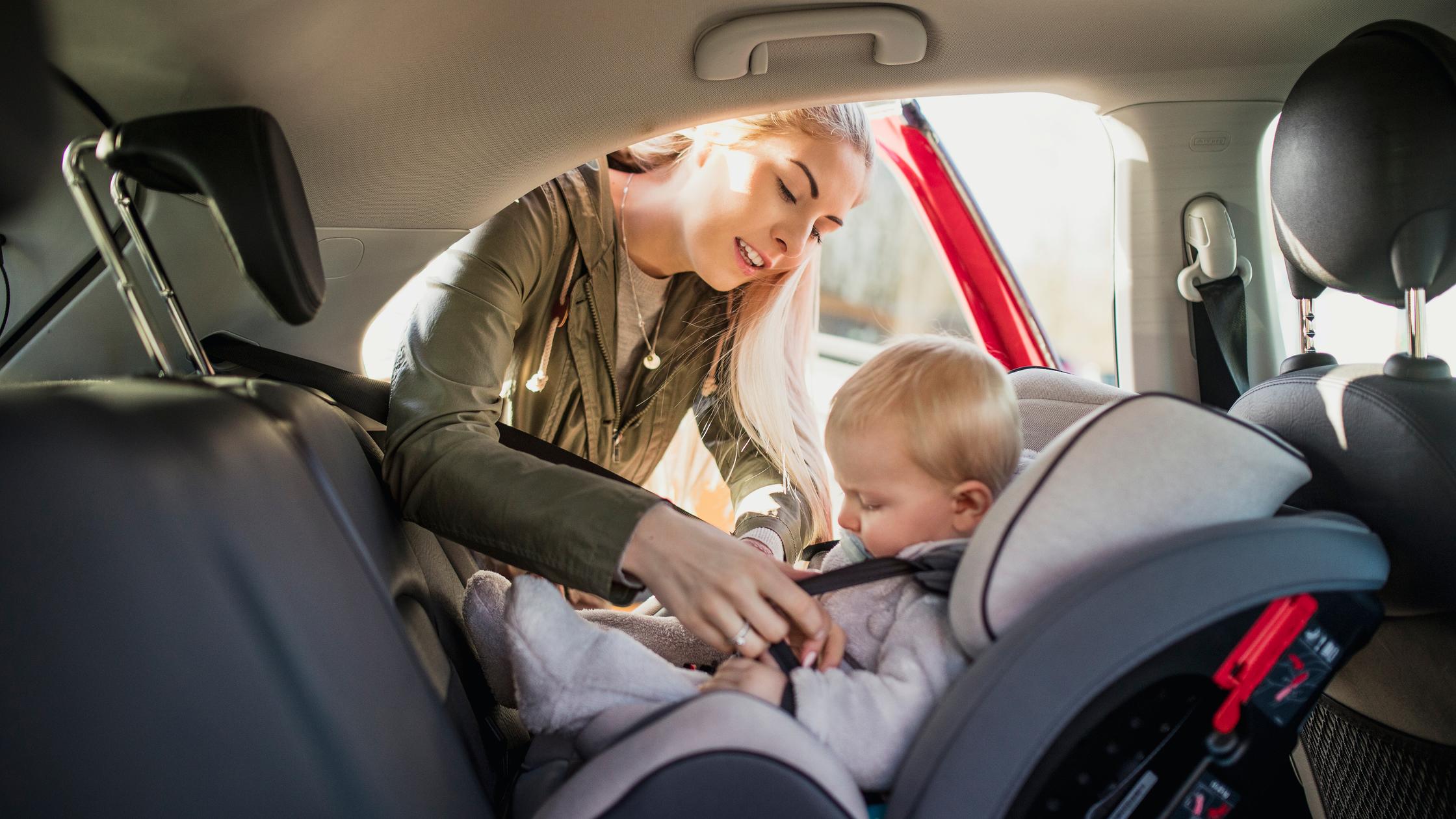 Mother fitting safety belt in car on her child