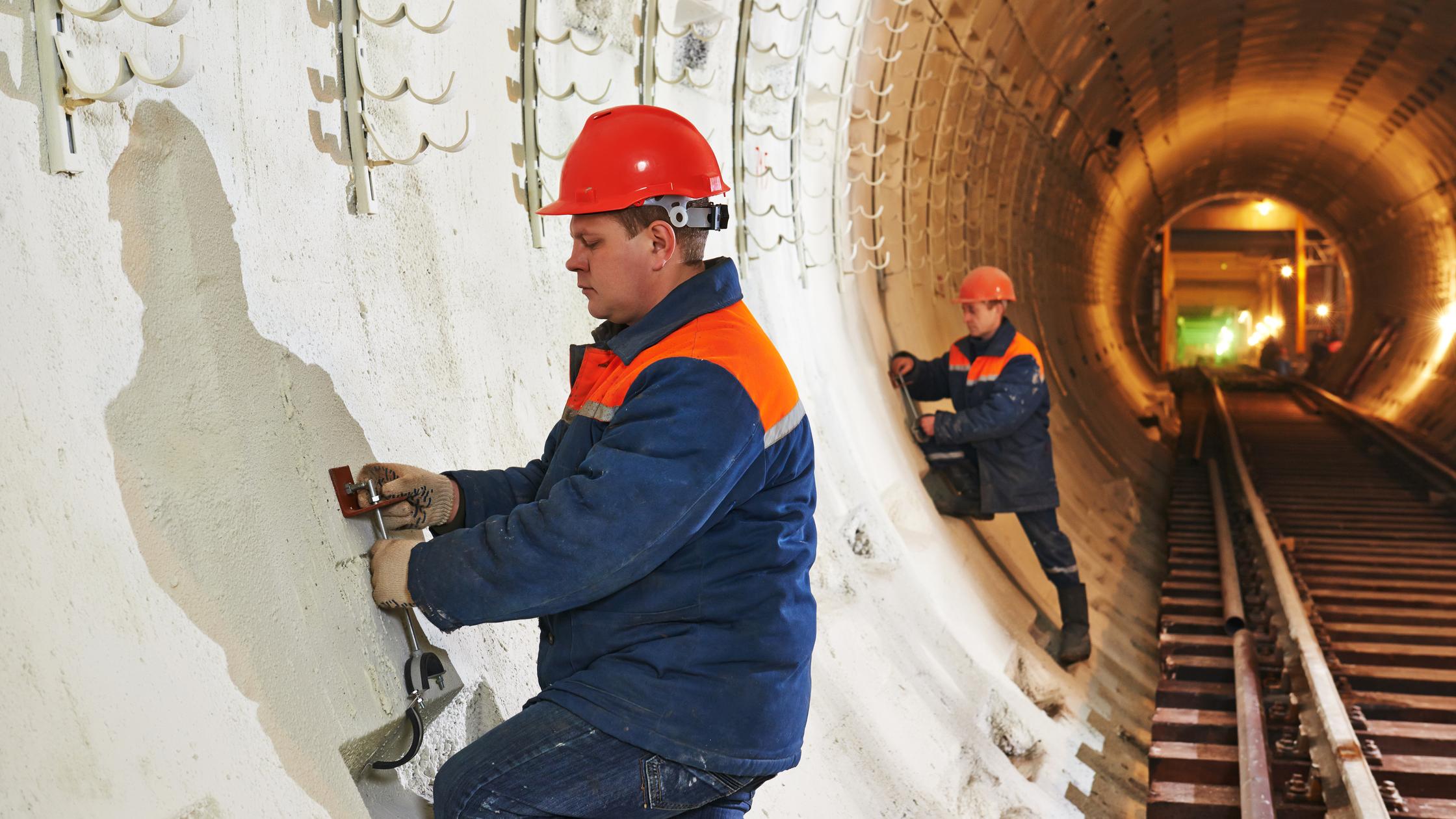 Identify - Tunneller worker installing fixture in underground subway metro construction site