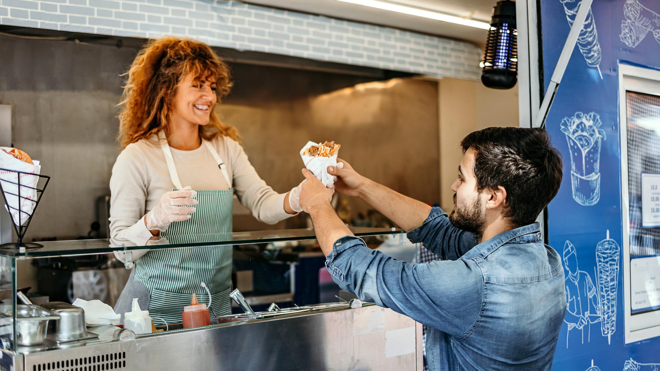 A woman selling food to a man on a truck