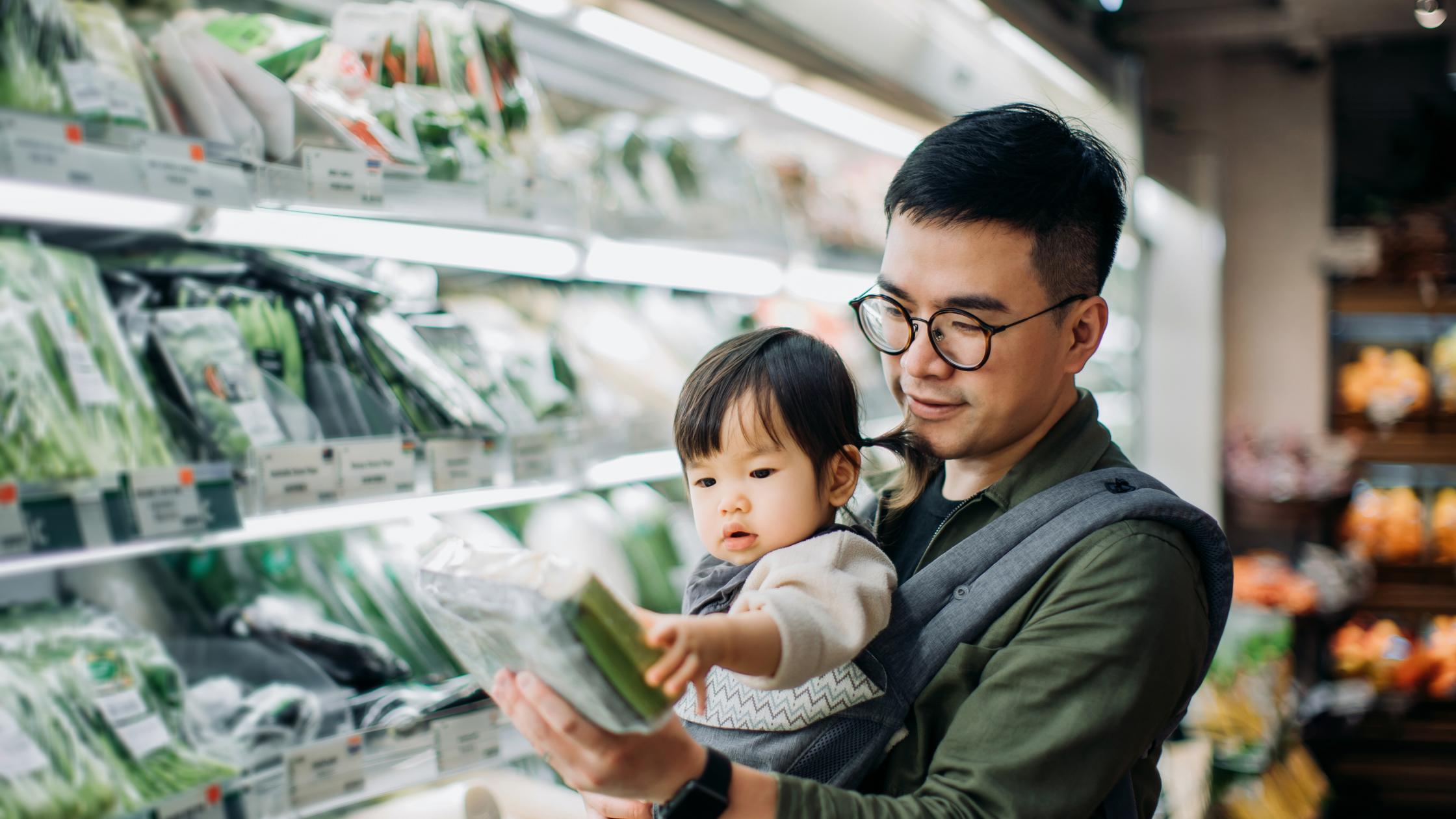 Father with little daughter grocery shopping for fresh organic vegetables in supermarket.