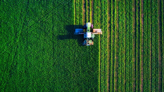 Tractor mowing a green field, aerial view.