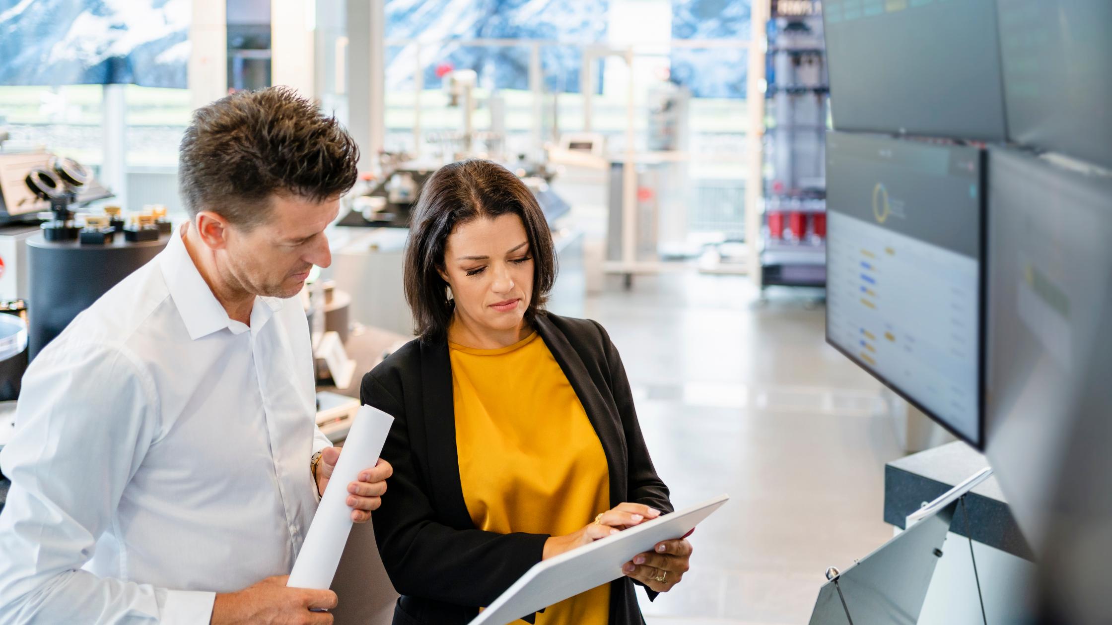 Businessperson using tablet PC standing by colleague in industry.