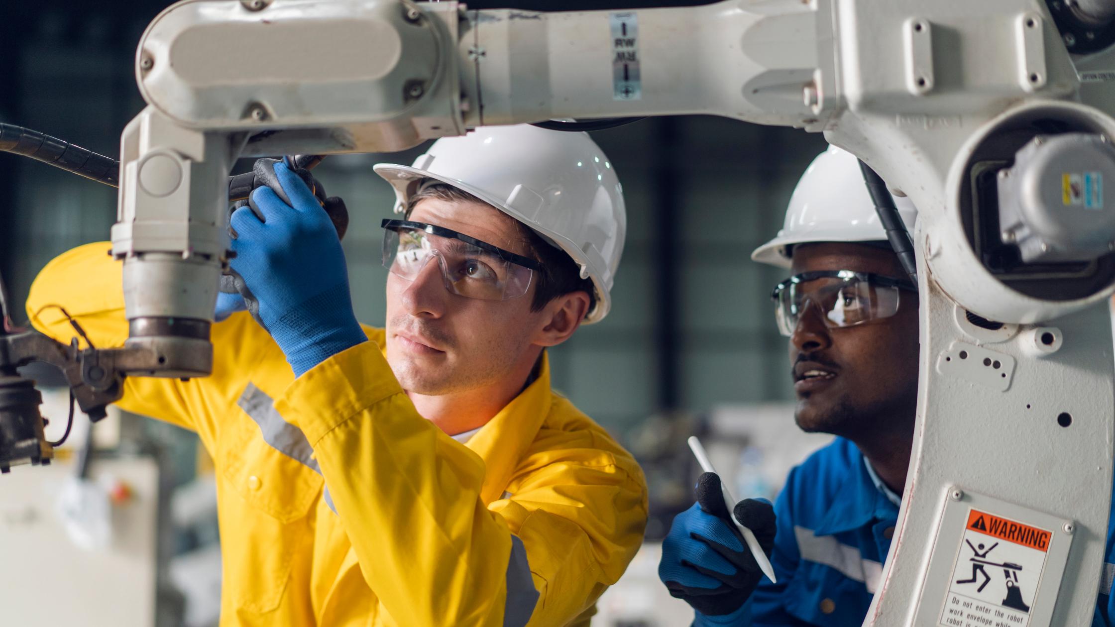 Two men examining robotic product in factory