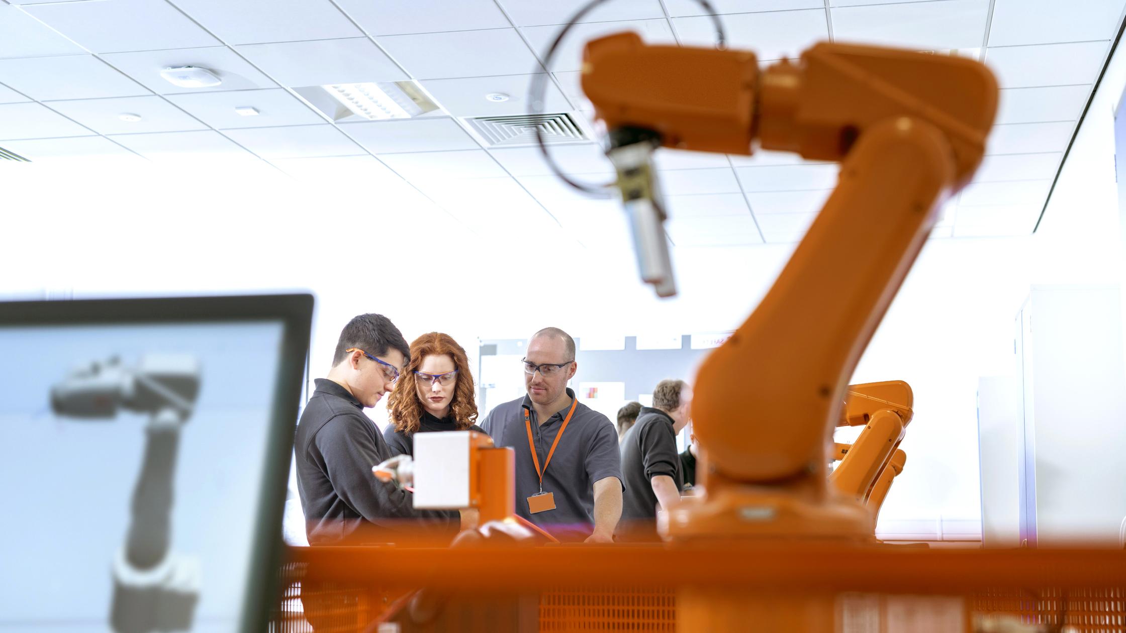 Robotics apprentices using test industrial robots in robotics facility