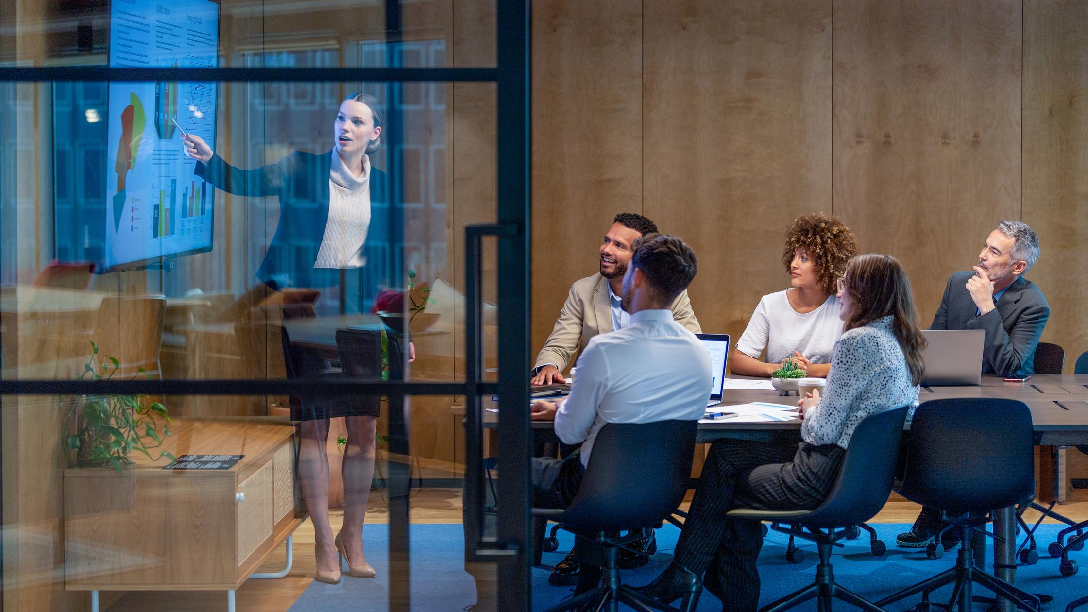 Connect Plus - Woman giving a data presentation on a tv in a board room