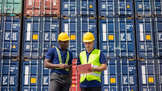 Two Commercial dock workers examining and confirm shipment at cargo container yard