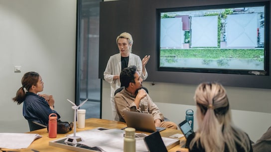 Colleagues brainstorming together in an office and looking at their screen