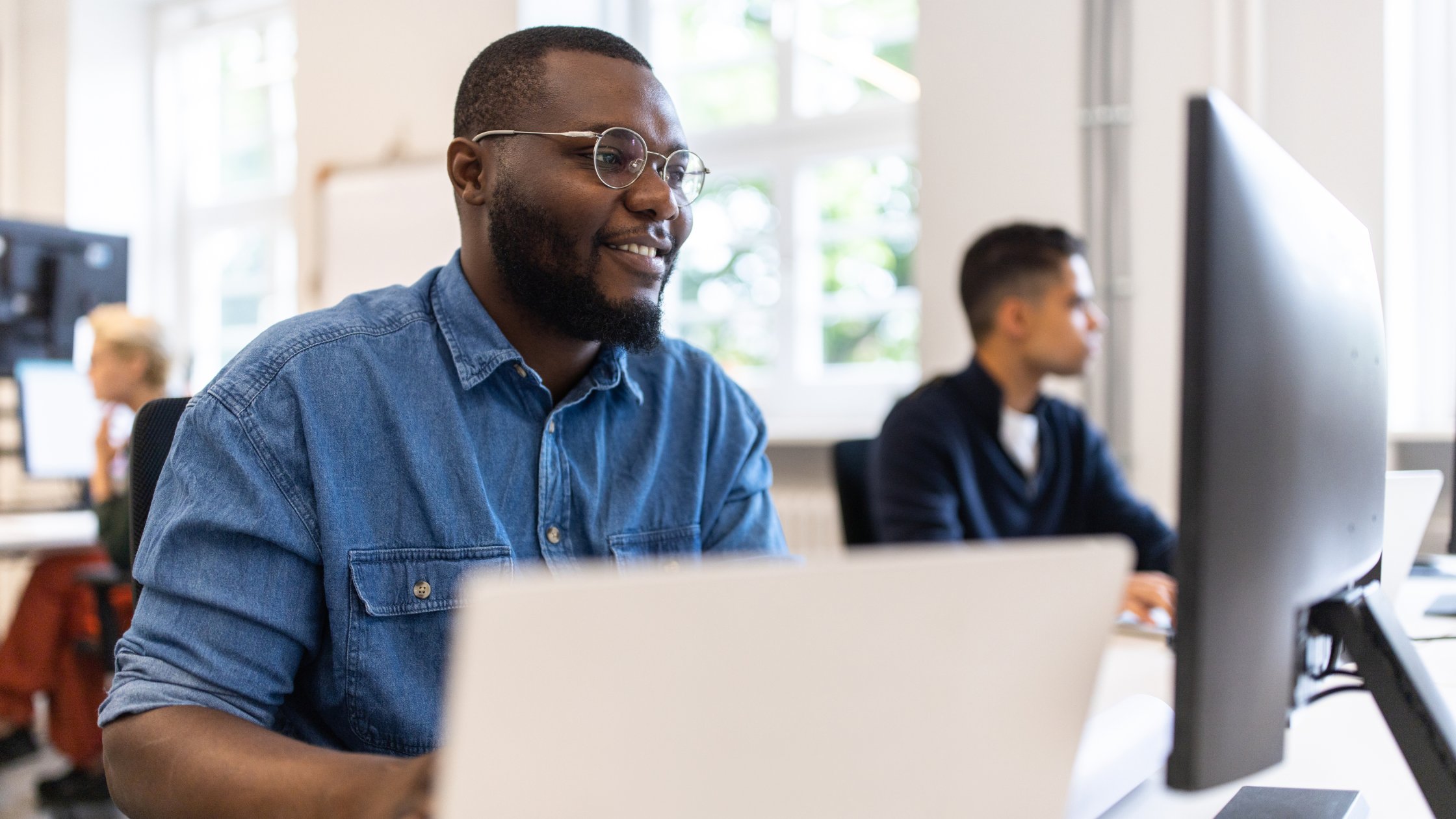 Male IT professionals sitting at desk working on computer at startup.