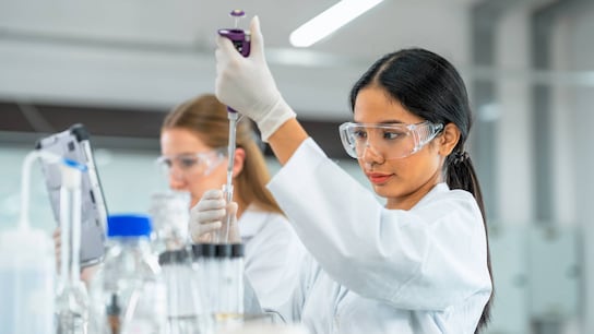Biologists put chemical liquid with the pipette in a test tube inside a laboratory.