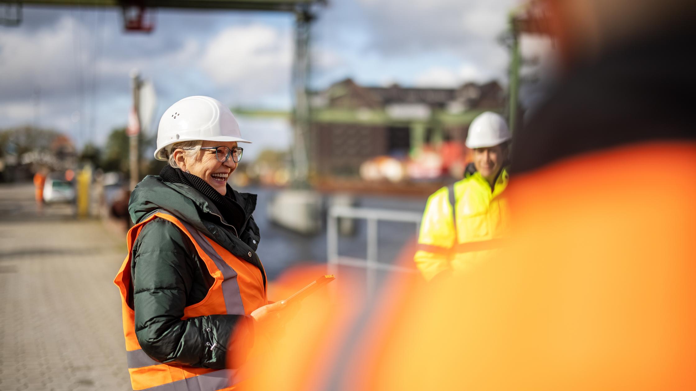 Senior woman manager laughing with team at large commercial dock