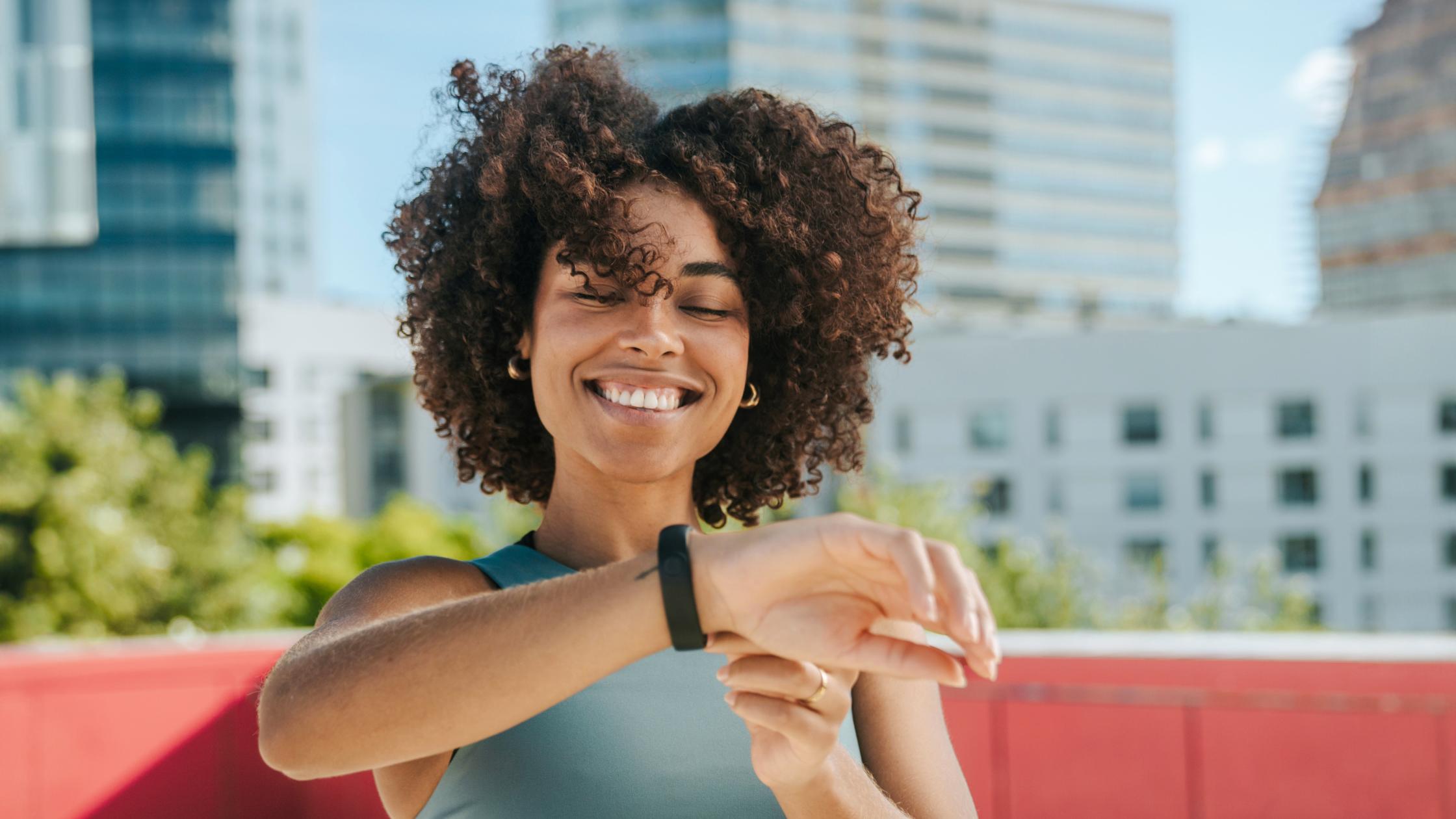 Person looking at smart watch on a rooftop in Barcelona with buildings on the background.