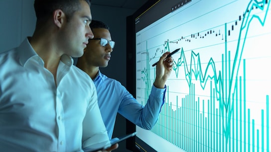 Businessmen studying graphs on an interactive screen in business meeting