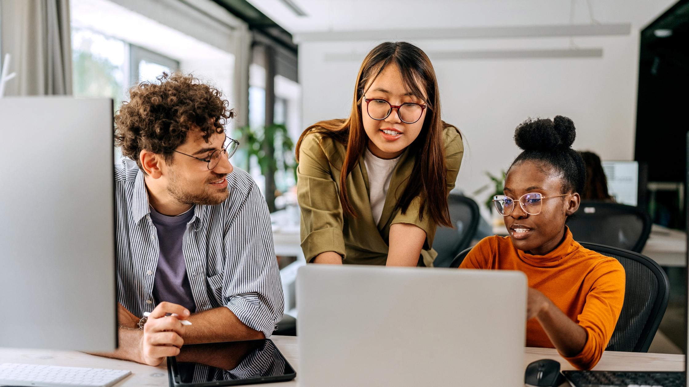 Three young colleagues discussing work at modern office.