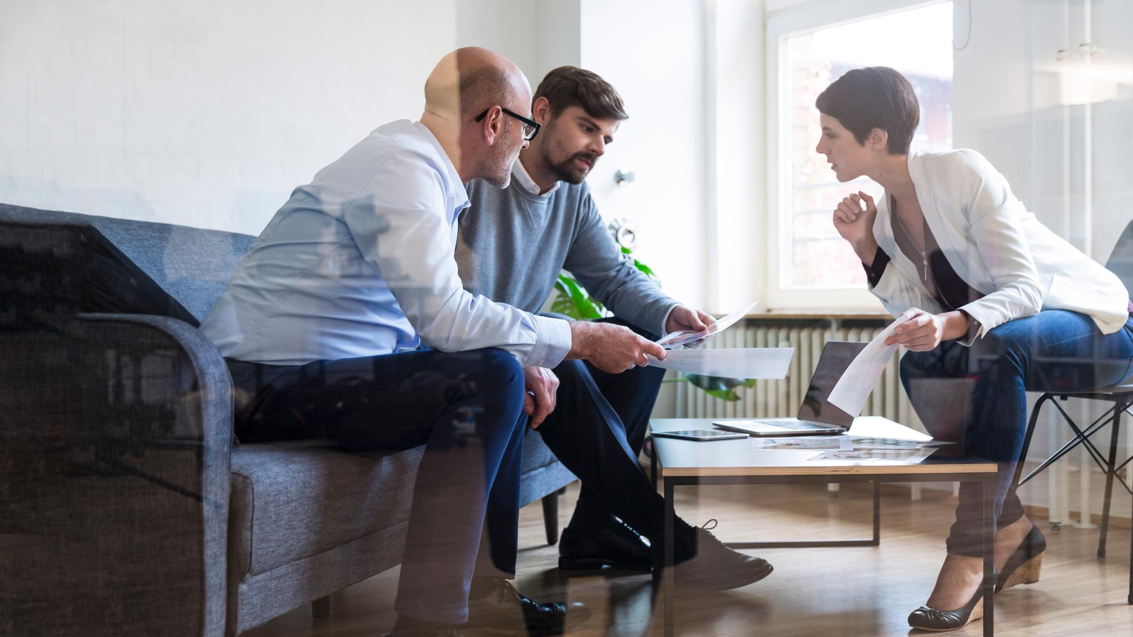 Three experts sat talking in business room