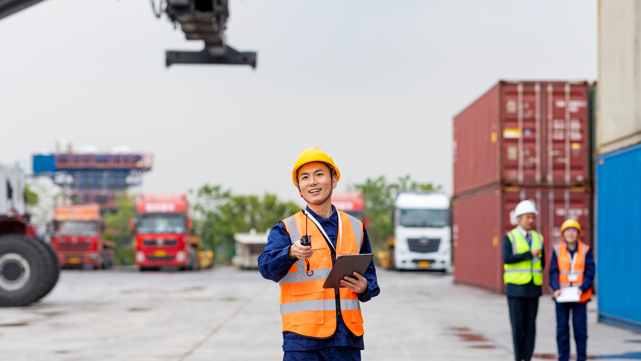 Male shipping control engineer standing in front of cargo container.