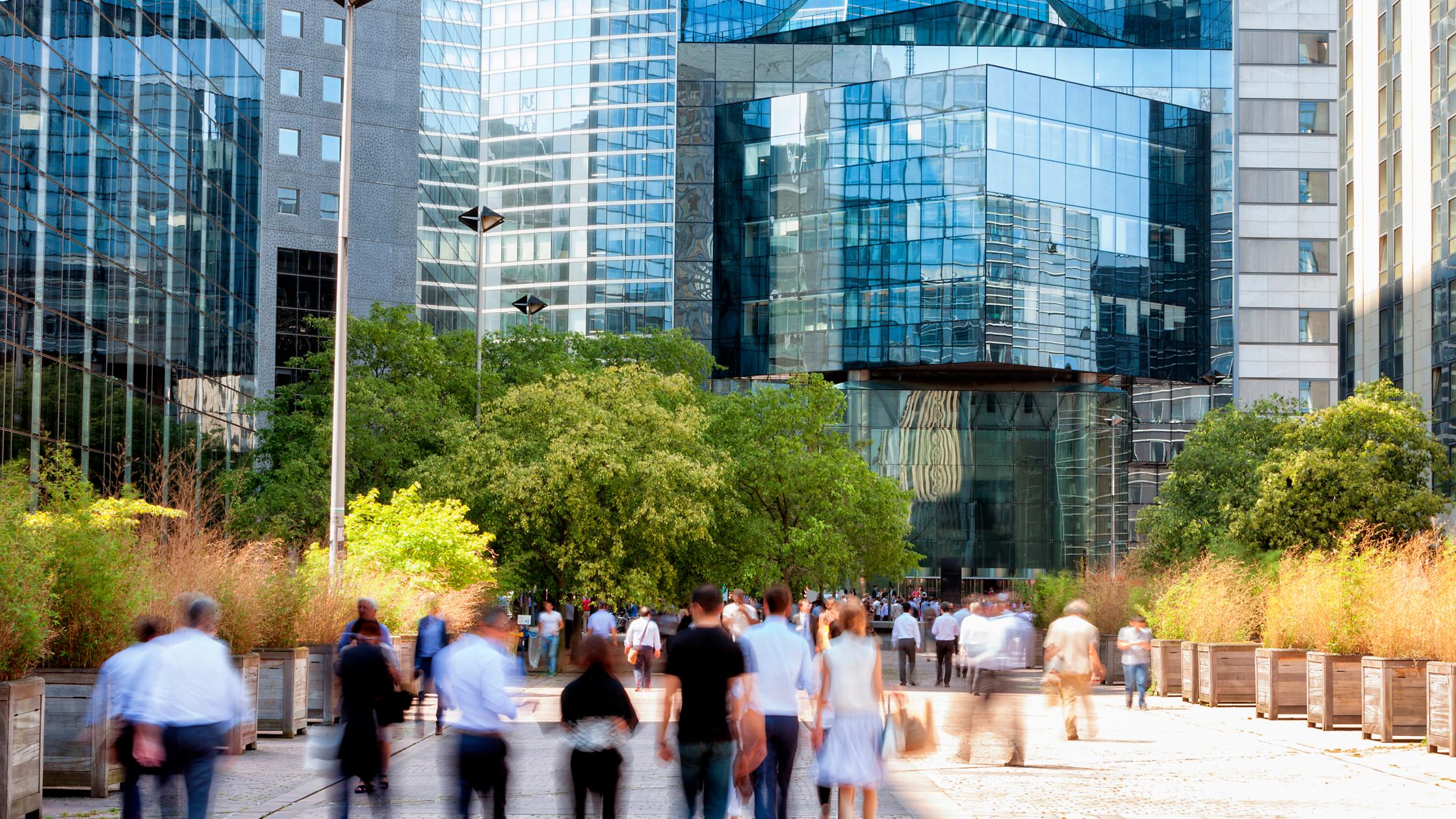Crowd of business people walking through financial district towards modern office building, La Defense, Paris, France