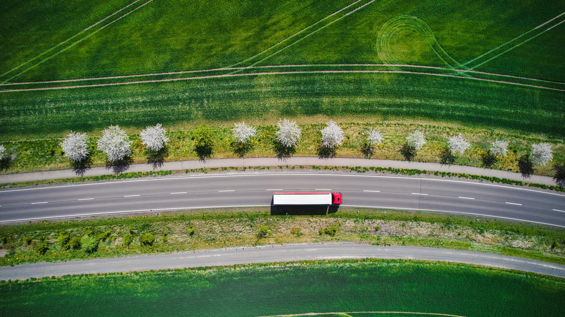 Drone shot direct above a truck moves along a single road.
