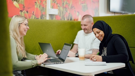Coworkers seated at a table and working togheter with their laptop